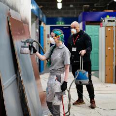Female student using paint sprayer on door
