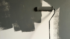 Paint roller spreading paint onto wall