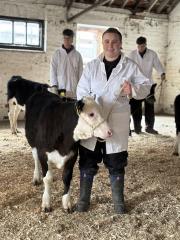 Female student standing with small cow