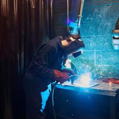 Engineer welding metal with blue sparks flying