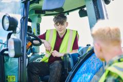 Student wearing hi-vis sitting in tractor talking to teacher