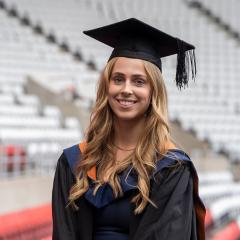 Student in graduation cap and gown smiling at camera